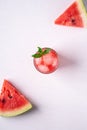 Fresh cold watermelon juice with ice cubes and green mint leaf in glass drink close to two slices of watermelon, top view Royalty Free Stock Photo