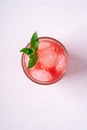 Fresh cold watermelon juice with ice cubes and green mint leaf in glass drink on white background, top view