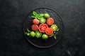 Fresh colored tomatoes in a black plate. Vegetables.