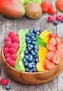 Fresh colorful fruits and berries in wooden bowl on rustic table Royalty Free Stock Photo