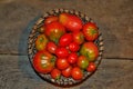 Fresh cherry tomatoes and basil in a wooden plate on a dark background. Harvesting tomatoes Royalty Free Stock Photo