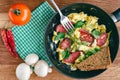 Fresh cooked scrambled eggs in pan with sausage and herbs. Tomato, chilli pepper, mushrooms on wooden board, top view. Royalty Free Stock Photo