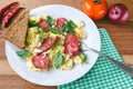 Fresh cooked scrambled eggs with sausage and herbs in white plate.Bread, napkin, fork, vegetables on wooden board. Royalty Free Stock Photo