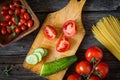 Fresh cooking ingredients on wooden cutting board. Tomatoes and cucumbers Royalty Free Stock Photo