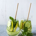 Fresh cool detox water drink with cucumber and lemon. Two glass of Lemonade with basil and mint leaves. Concept of proper Royalty Free Stock Photo