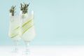 Fresh cool lemonade of cucumber with ice cubes, rosemary, lime in two wineglasses on white and pastel green background, copy space Royalty Free Stock Photo