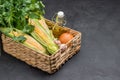 Fresh corn cobs, bunch of parsley, oil in bottle, and garlic in wicker basket