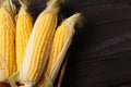 Fresh corn on cobs on wooden table, closeup, top view. Dark background with copy space Royalty Free Stock Photo