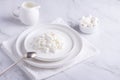 Fresh cottage cheese grain in a white bowl and marshmallows. Curd in granules with cream. Copy space Royalty Free Stock Photo