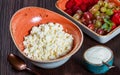 Fresh cottage cheese with juicy berries raspberries, strawberry and grapes on dark wooden background.