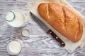 Fresh cow`s milk and a loaf of white, warm, soft bread on a wooden table, top view Royalty Free Stock Photo