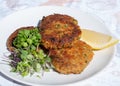 Fresh crab cakes served on a white plate with lemon and salad Royalty Free Stock Photo