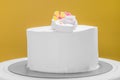 Isolated fresh cream frosted cake with flowers against yellow background