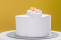 Isolated fresh cream frosted cake with flowers against yellow background