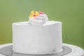 Fresh cream frosted cake with ornament flowers against green background