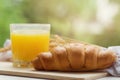Fresh crispy croissant and a glass of fresh juice on a wooden stand on a white wooden table in the garden. Healthy and tasty Royalty Free Stock Photo