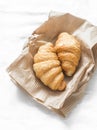 Fresh crispy croissants on a paper bag on a light background