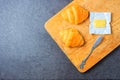 Fresh croissant and butter on wooden plate on stone table