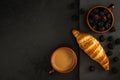 Fresh croissant with a cup of coffee and berries in a mug on a black concrete background with a stone cutting board. shot from Royalty Free Stock Photo