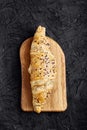 Fresh croissant, cutting wooden board, black background. Top view