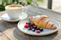 Fresh croissant topped with summer berries, served with cappuccino at cozy outdoor street cafe Royalty Free Stock Photo