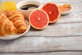 Fresh Croissants with coffee, jam and orange juice for breakfast on rustic wooden background. Royalty Free Stock Photo