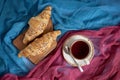 Fresh croissants and cup of black tea on colorful background.