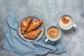 Fresh croissants and a cup of coffee with hearts. Gray grunge background. Top view, copy space