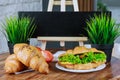 Fresh croissants with pork chicken tomatoes cucumbers salad on a white plate on a wooden table. Black Copy space Royalty Free Stock Photo