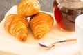 Fresh croissants, spoon and honey jar over wooden board, breakfast, selective focus and close-up Royalty Free Stock Photo