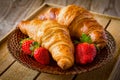 Fresh croissants with strawberries on plate, breakfast food, warm tone Royalty Free Stock Photo