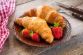 Fresh croissants with strawberries on plate, breakfast food, warm tone Royalty Free Stock Photo