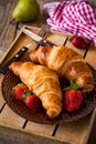 Fresh croissants with strawberries on plate, breakfast food, warm tone Royalty Free Stock Photo