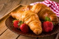 Fresh croissants with strawberries on plate, breakfast food, warm tone Royalty Free Stock Photo