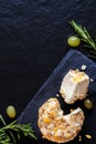 Fresh crotten farm goat cheese with pieces of mango, hazelnut and pineapple dark black background with grapes and