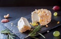 Fresh crotten farm goat cheese with small pieces of mango, hazelnut and pineapple and cut wedge with grapes and rosemary