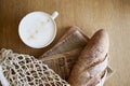 Fresh crust baguette with cappuccino on newspaper wooden table. French traditional morning