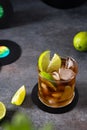 Fresh Cuba Libre cocktail with cola, lime and mint on dark background with vinil records. Alcoholic, non-alcoholic beverage.