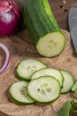 Fresh cucumbers, partly sliced, on chopping board with knife