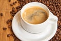 Fresh cup of coffee surrounded by coffee beans on a wooden background Royalty Free Stock Photo