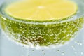 Fresh cut lime floating in soda water glass with bubble on yellow background. Healthy commercial fruit photography Royalty Free Stock Photo