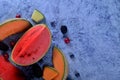 Fresh cut melons, watermelon and berries on a blue stone background