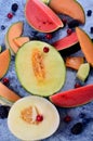 Fresh cut melons, watermelon and berries on a blue stone background Royalty Free Stock Photo