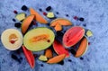 Fresh cut melons, watermelon and berries on a blue stone background