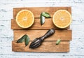 Fresh cut oranges with leaves and a wooden crush for fruit, on rustic wooden tray, top view Royalty Free Stock Photo