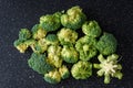 Fresh cut up florets of broccoli ready for cooking, large black cutting board Royalty Free Stock Photo