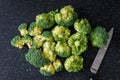 Fresh cut up florets of broccoli ready for cooking, large black cutting board, paring knife Royalty Free Stock Photo