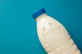 Fresh dairy product in full plastic bottle for milk, kefir or yoghurt with blue cap in center of blue background. Top view