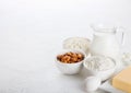 Fresh dairy products on white table background. Glass jar of milk, bowl of cottage cheese and baking flour and almond nuts. Eggs a