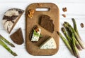 Dark sliced bread, blue cheese with nuts on wooden cutting board decorated with asparagus. Flat lay, top view Royalty Free Stock Photo